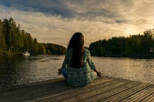 een vrouw zit te mediteren bij een meer