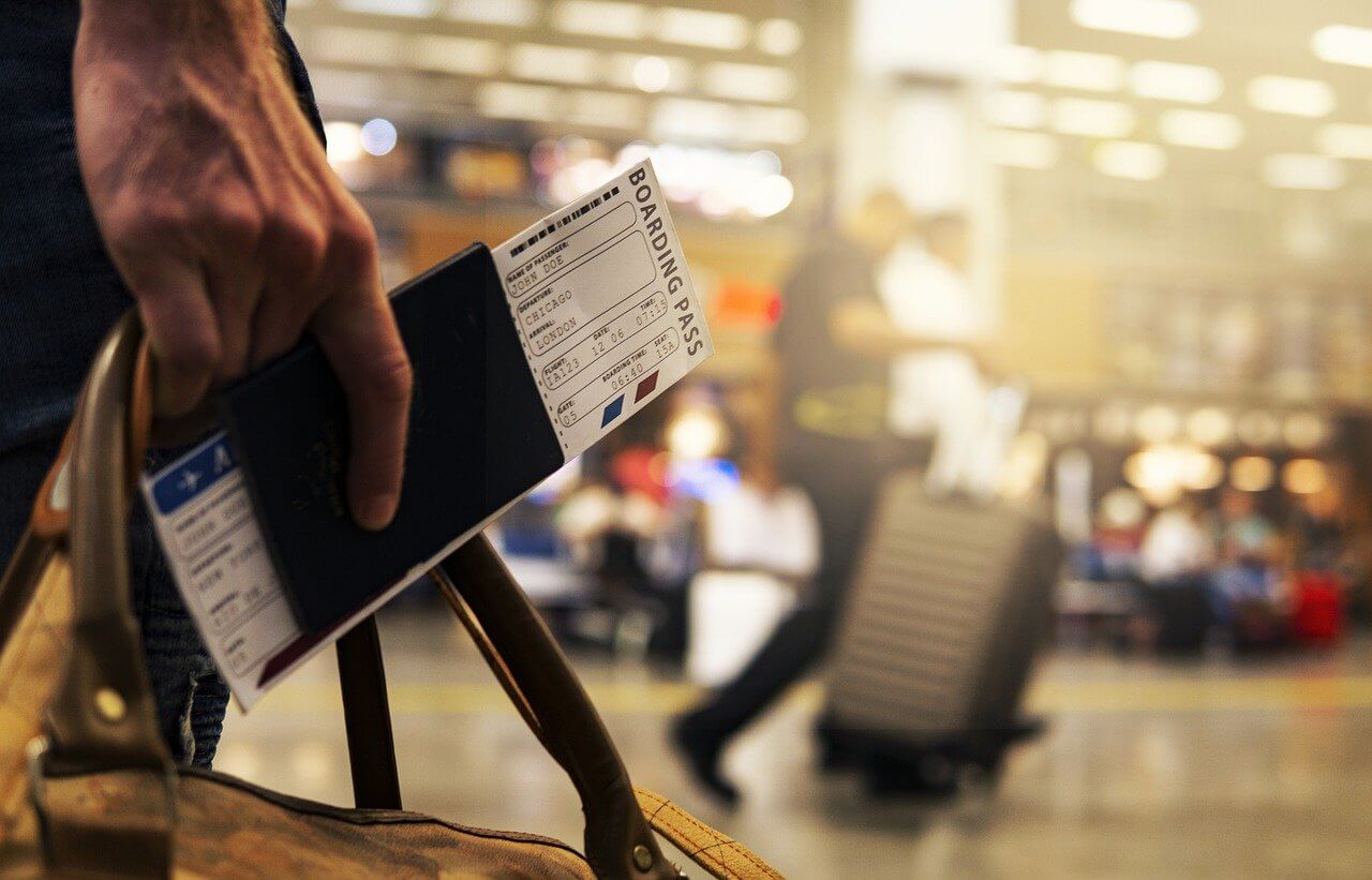 hand houdt paspoort en vliegticket vast