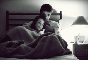 vriend en vriendin kijken film in bed onder dekentje