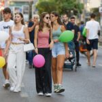 groepje jongeren loopt over straat met ballonnen in hun hand
