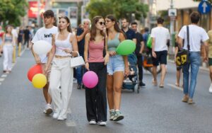 groepje jongeren loopt over straat met ballonnen in hun hand