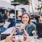 man en vrouw zitten op terras. Man maakt foto van vrouw