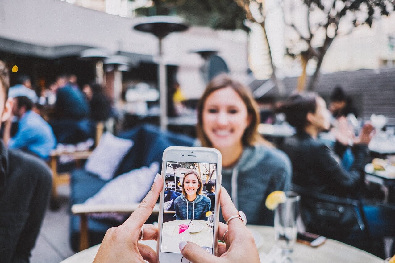 man en vrouw zitten op terras. Man maakt foto van vrouw